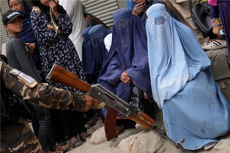 Taliban verbieten Universitätsbildung für Frauen Straßenszene in Kabul: Ein bewaffneter Taliban-Kämpfer steht neben vollverschleierten Frauen. Die Islamisten haben Frauenrechte massiv eingeschränkt.