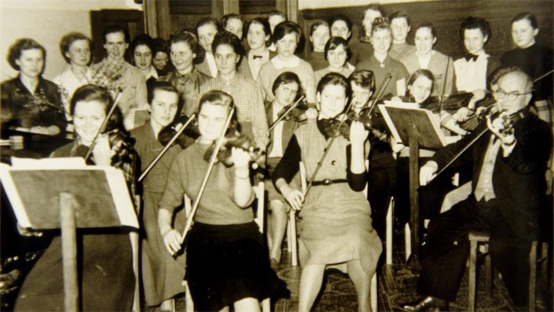 Das historisches Bild zeigt ein jugendliches Streichorchester.