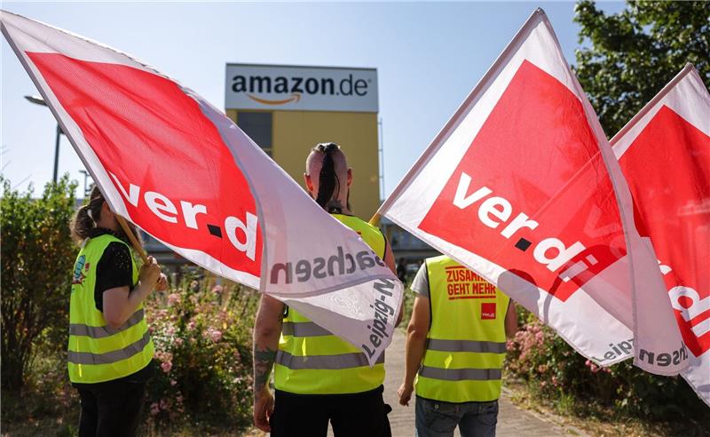 Verdi ruft zum Black Friday zu Warnstreik bei Amazon auf Streikende stehen mit Fahnen von Verdi vor einem Verteilzentrum des Online-Händlers Amazon in Leipzig. (Archivbild)
