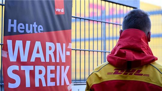Streikposten am Werkstor: Ein DHL-Mitarbeiter hat die Arbeit niedergelegt und schaut auf eine Zustellbasis, in der er sonst arbeitet. 