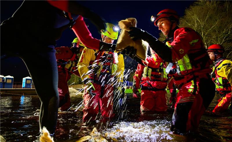 Strömungsretter der DLRG sichern mit Sandsäcken einen Deich.