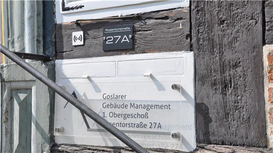Hausfassade mit Schild 'Goslarer Gebäude Management 1. Obergeschoß Ventorstraße 27A' und schwarzem Türschild '27A'