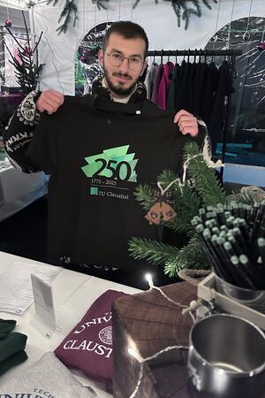 Die Clausthal-Zellerfelder erfinden ihren eigenen Weihnachtsmarkt Student Leith Echty präsentiert (und verkauft) die Shirts zum 250. Geburtstag der TU Clausthal.