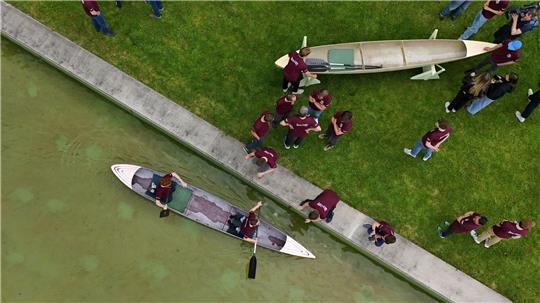 Studenten und Studentinnen der Bauhaus-Universität Weimar fahren mit dem Betonkanu auf dem Wasser im Weimarer Schwanseebad. (Aufnahme mit einer Drohne)