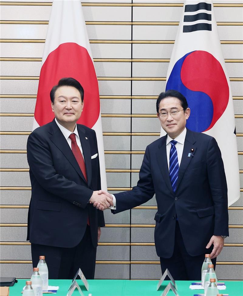 Südkoreas Präsident Yoon Suk Yeol (l.) und Japans Premier Fumio Kishida reichen sich vor ihren Gesprächen die Hände.