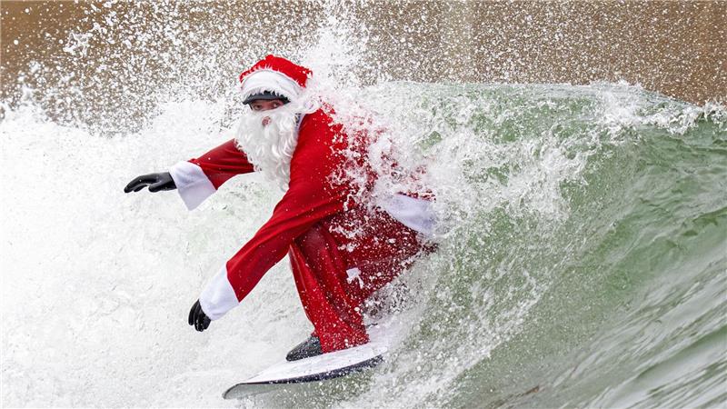 Surflehrer und Rettungsschwimmer Finn Clark aus Gorebridge verkleidet sich als Weihnachtsmann für eine Surfsession im Lost Shore Surf Resort in Newbridge, in der Nähe von Edinburgh.
