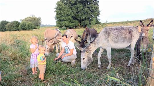 Susanne Goos aus Rhüden kümmert sich um die zwölfköpfige Eselherde und freut sich über Kinderbesuch – wie hier von Maja und Elias Schmidt aus Bad Harzburg. Foto: Biener