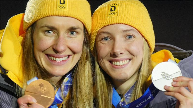 Susanne Kreher und Jacqueline Pfeifer zeigen bei der Siegerehrung ihre Medaillen bei den Olympischen Winterspielen Mailand Cortina 2026.