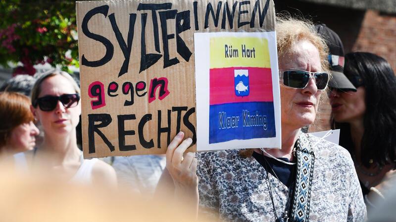 „SylterInnen gegen Rechts“ steht auf einem Schild, dass eine Frau bei einer Mahnwache in der Hand hielt. Im Strönwai, wo sich auch der Pony-Club befindet, hatten sich zahlreiche Menschen anlässlich des um Rassismus-Eklats um ein Partyvideo auf Sylt versammelt und wollen ein Zeichen gegen Rassismus setzen.