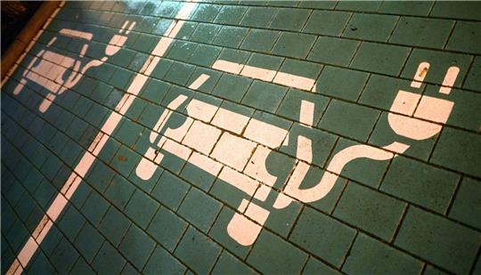 Symbole markieren Parkplätze mit einer öffentlichen Ladesäule für Elektroautos.