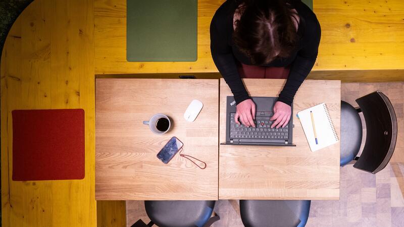 Symbolfoto: Eine Frau sitzt im Homeoffice am Küchentisch und arbeitet an einem Laptop.
