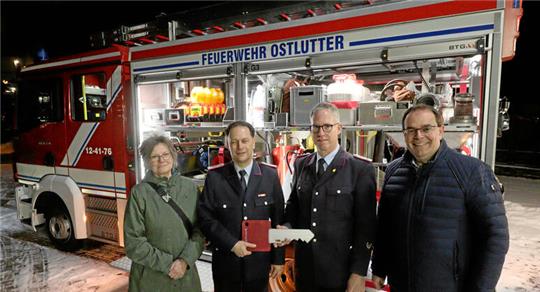 Vier Personen stehen vor einem Feuerwehrfahrzeug und präsentieren einen symbolischen Schlüssel.