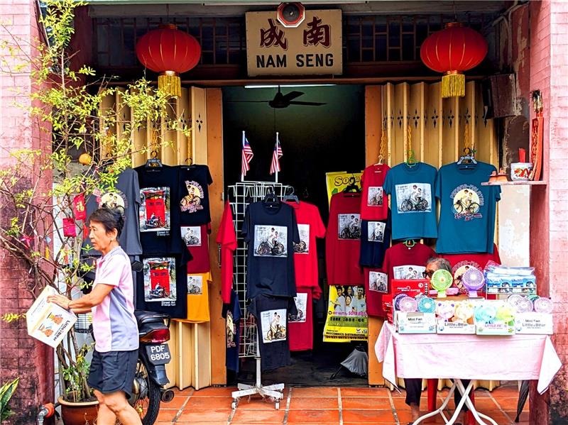 Penangs berühmte Street Art: „Malaysias Antwort auf Banksy” T-Shirts und andere Dinge, auf denen Street Art-Kunstwerke aus Penang abgebildet sind, werden in einem Geschäft zum Kauf angeboten.