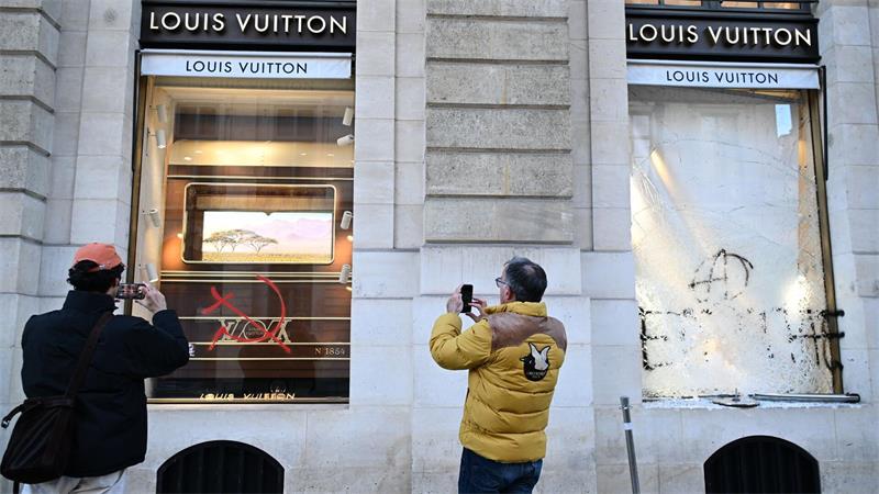 Tag nach Ausschreitungen in Frankreich: Passanten fotografieren Graffiti an Louis Vuitton Geschäft