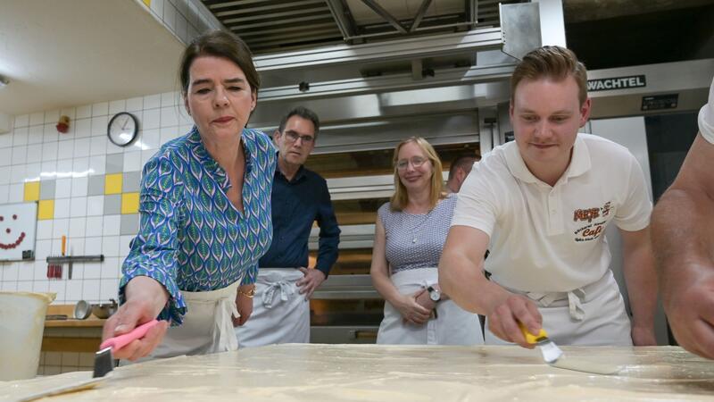 Tagesschau-Sprecherin Susanne Daubner (l) und Bäckermeister Vincent Richter von der Bäckerei Meye verteilen den Sulf-Belag auf dem weltgrößten Mohnkuchen.