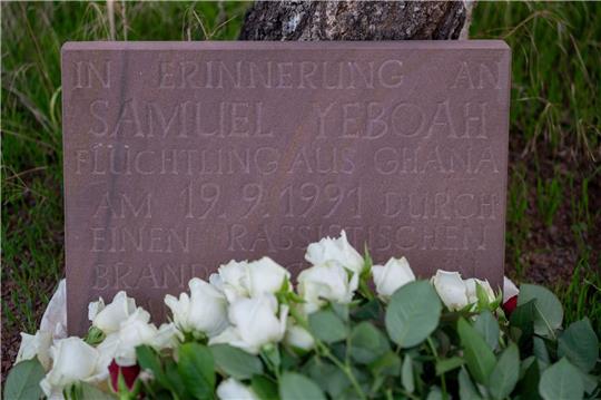 Teilnehmer der Gedenkkundgebung für den 1991 bei einem Brandanschlag getöteten ghanaischen Asylbewerber Samuel Yeboah haben an einem Gedenkstein Blumen abgelegt.