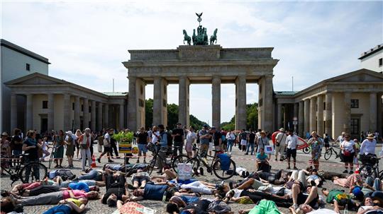 Teilnehmer einer Demonstration des Bündnisses „BaumEntscheid“ liegen auf dem Boden auf dem Pariser Platz und simulieren einen Hitzetod.