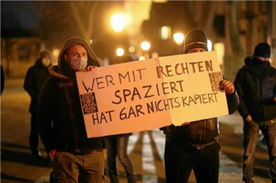 Teilnehmer einer Gegendemonstration stehen auf dem Domplatz in Halberstadt mit einem Plakat. Foto: Bein/dpa