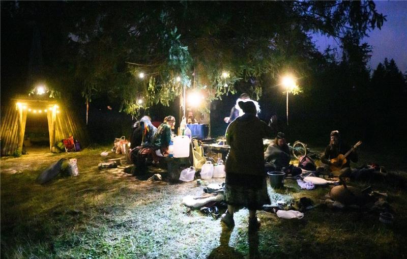 Teilnehmer sitzen bei einem Zeltlager inmitten des Waldes. 