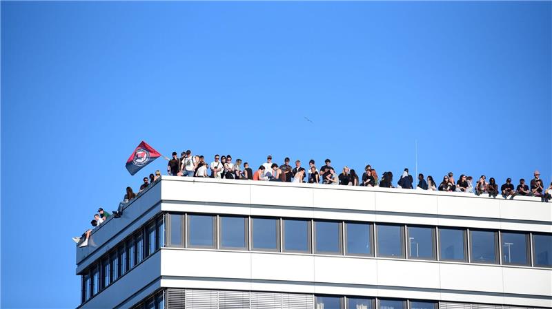 Teilnehmer stehen bei einer Demonstration mit dem Motto „Krieg und Krise haben System. Als Klasse vereint: Sozialismus erkämpfen!“ auf dem Dach eines Hauses in Hamburg.