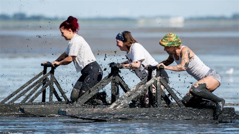 Teilnehmerinnen starten bei den deutschen Meisterschaften im Schlickrutschen im Rahmen des „Watt en Schlick Fest“ am Strand von Dangast.