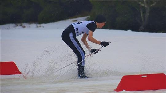 Das Foto zeigt einen Skilangläufer, der durch eine Pfütze fährt.