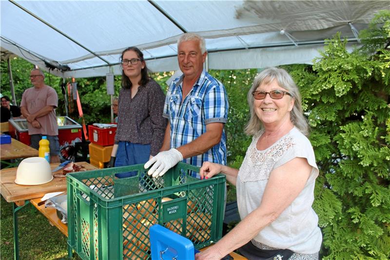 Schulenberg feiert und erhält spontane Hilfe Tessa Pillach (v. li.), Andreas Thäsler und Shirley Beck bereiten die Spanferkel-Brötchen zu. Foto: Wendt