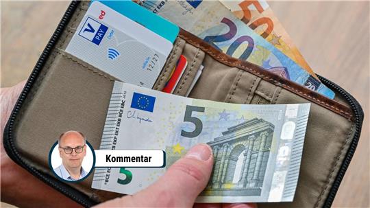 Eine Frau hält in ihrer Hand eine Brieftasche mit Geld und Bankkarten.