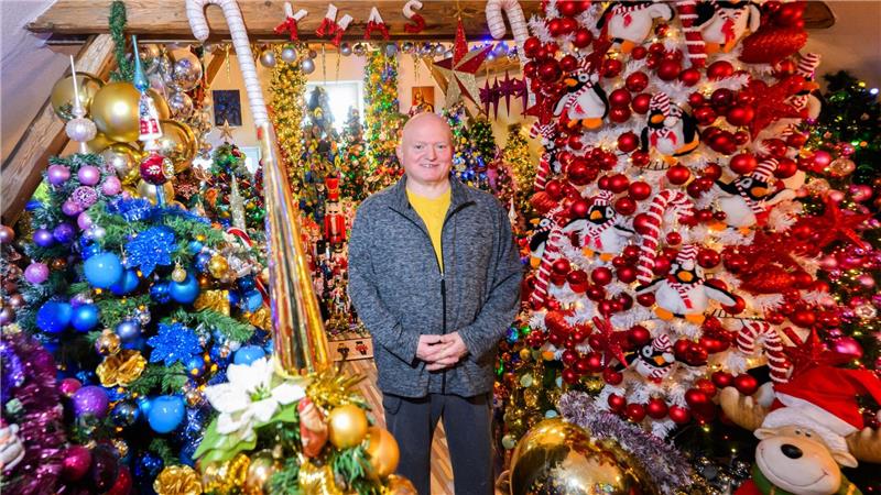Thomas Jeromin steht inmitten von Weihnachtsbäumen in seinem Haus im Landkreis Schaumburg. 