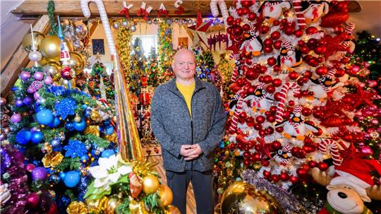 Thomas Jeromin steht inmitten von Weihnachtsbäumen in seinem Haus im Landkreis Schaumburg. 