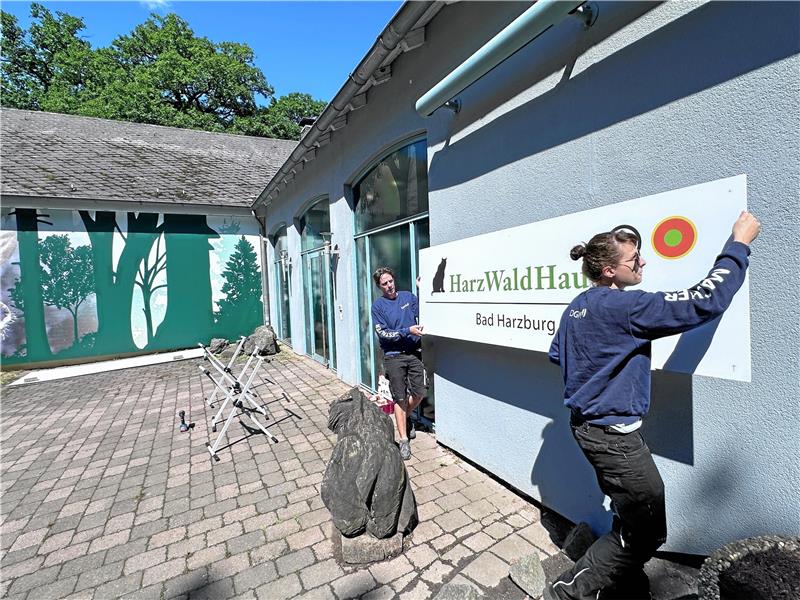 Thorsten Büttner und Jacquline Nemow von der Gestaltungsagentur DGM aus Roßdorf bringen das neue Schild am Eingang des Harzwaldhauses an. Foto: Schlegel