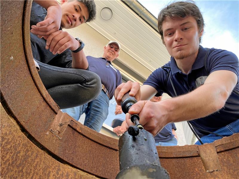 Till Diegeler (r.), Jonathan Chibungo (l.) und Christoph Willeke (nicht im Bild) schmieren die Erdachse, Pur-Vorsitzender Joachim Niemeyer überwacht die Arbeiten. Links im Bild ein Blick auf die Achse, der sich nur einmal im Jahr, nämlich am 3. Juni, bietet. Fotos: Schlegel