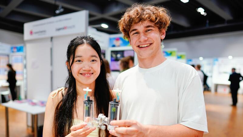 Tina Thao-Nhi Schatz und Anthony Eliot Striker aus Berlin, Sieger im Fachgebiet Biologie, halten eine Vorrichtung in den Händen, mit deren Hilfe sie Bakterien für Brennstoffzellen erforschen.