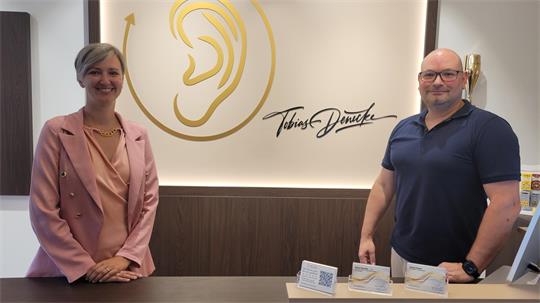 Eine Frau und ein Mann stehen nebeneinander und lächeln in die Kamera.