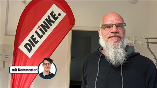 Tobias Schwerdt neben einem Aufsteller der Partei die Linke.