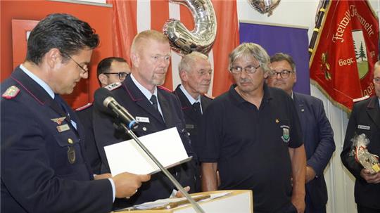 Tobias Thurau (l.) ehrt Wolfgang Lueg (erste Reihe, 3.v.l.) für 40-jährigen Dienst in der Feuerwehr.