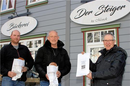 Tobias und Peter Moock freuen sich über die 5000 bedruckten Brötchentüten, die Dr. Klaus George (von links) vom Geopark dabei hat.  Foto: Knoke