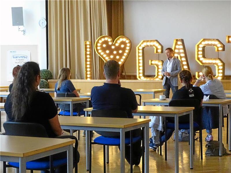 Tom Derer, Geschäftsführer der Luchs-Akademie, stellt das Projekt „I love Gastro“ in der Aula der BBS Wichernstraße vor. Gekommen sind zum Start des neuen Jahres Vertreter aus Betrieben, der Dehoga und der Berufsbildenden Schule. Foto: Exner