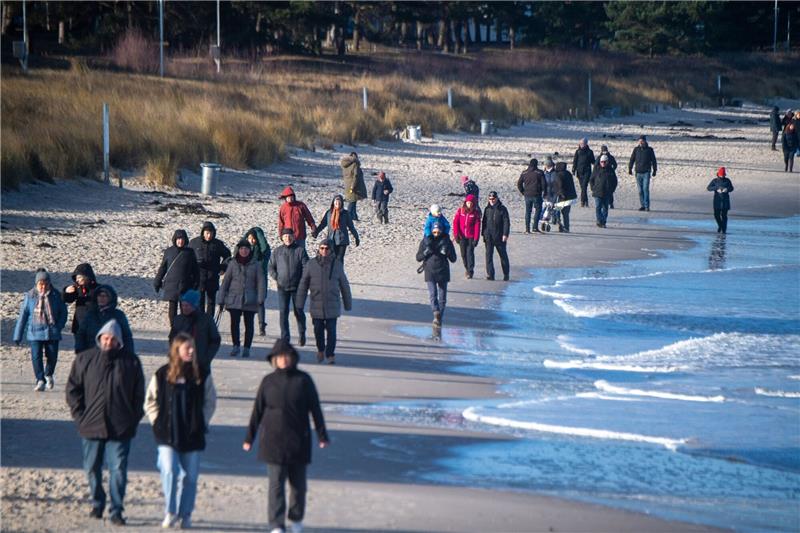 Touristen flanieren spazieren am Strand des Ostseebades auf der Insel Rügen.