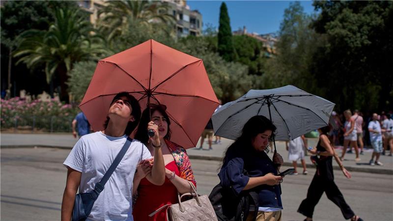 Heißester Tag des Jahres - Unwetter beenden die Hitzewelle Touristen schützen sich amvor der Kirche Sagrada Familia mit Regenschirmen vor der Sonne.
