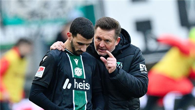 Trainer Christian Titz (r, Hannover 96) spricht bei der Einwechslung mit Waniss Taïbi (Hannover 96). 