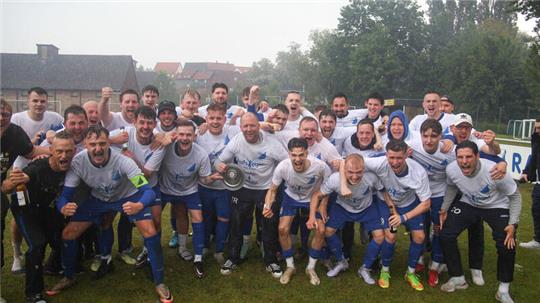 Trainer Dennis Gläser (M.) feiert mit Meisterschale und seinem Team den Aufstieg der FG Vienenburg/Wiedelah in die Bezirksliga.