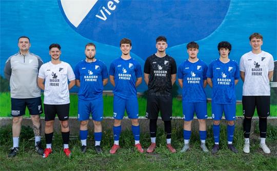 Acht junge Männer in Fußballtrikots und Sportkleidung stehen nebeneinander vor einer Wand mit einem großen blauen Kreis und dem Schriftzug Vienenburg.