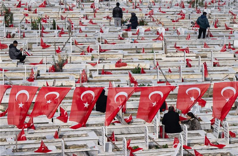 Gedenken und Wut ein Jahr nach Erdbeben in der Türkei Trauernde beten am Grab von Familienmitgliedern auf einem Friedhof in Antakya.