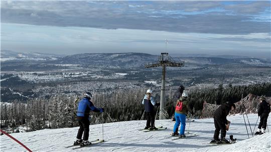 Das Foto zeigt Skifahrer, die ein leichtes Gefälle hinabrutschen.