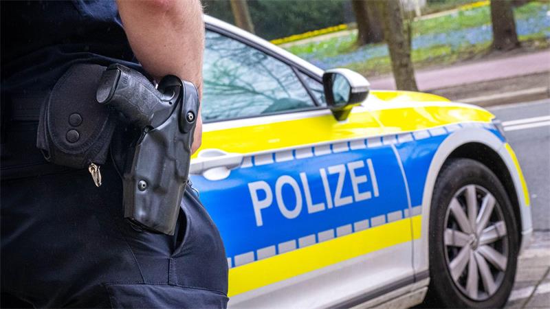 Ein Polizist steht vor einem Polizeiauto.