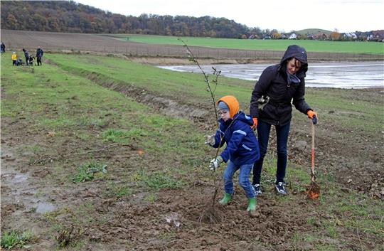 Trotz Regen und Matsch pflanzen Mama und Sohn einen Busch am neuen Sportplatz in Othfresen. Die beiden sind zwei von rund 30 Helfern beim Arbeitseinsatz des FC Othfresen. Foto: Hohaus