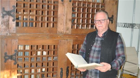 Typische Pose zum Abschied: Ulrich Albers steht mit geöffnetem Buch vor einem Archivschrank, wie er für die Zeit um 1500 typisch ist. Den Nachbau aus dem 19. Jahrhundert holte er in den 1990er Jahren vom Dachboden des Museums, wo es durchregnete.