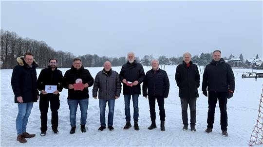 Das Foto zeigt acht Männer, die im Schnee stehen.