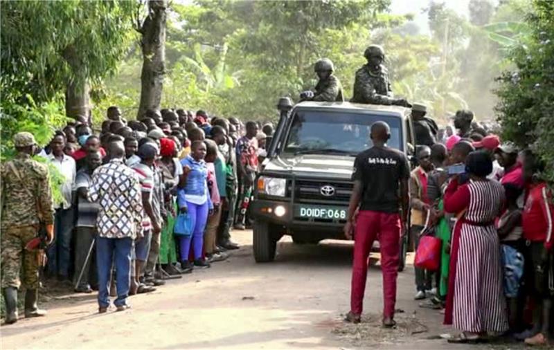 42 Schüler bei Angriff auf Schule in Uganda getötet Ugandische Sicherheitskräfte fahren an einer Menschenmenge vorbei, die sich nach dem Angriff vor der Schule in Mpondwe versammelt hat (Videostandbild).